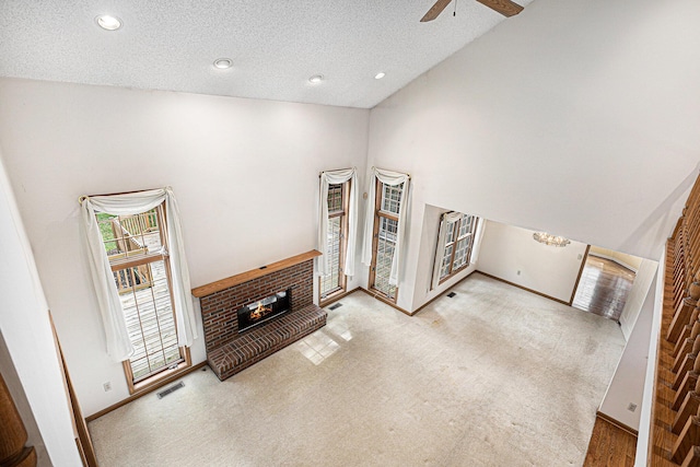 carpeted living room with a high ceiling, ceiling fan, a brick fireplace, and a textured ceiling