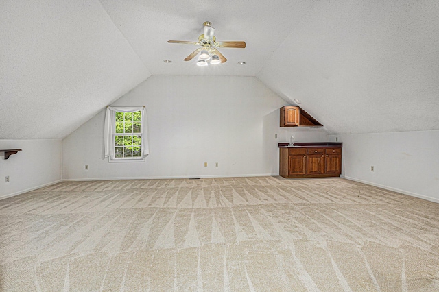 bonus room with lofted ceiling, light colored carpet, and a textured ceiling