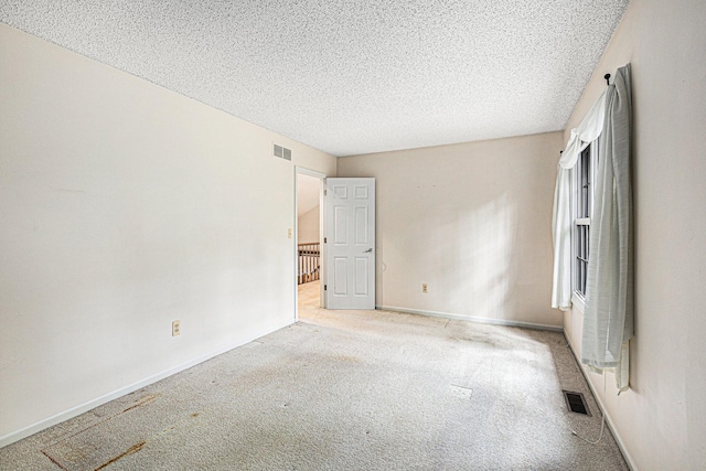 empty room featuring light colored carpet and a textured ceiling