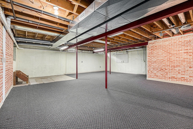 basement featuring brick wall and carpet flooring