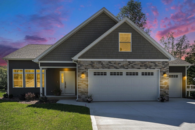 craftsman-style house featuring driveway, a front lawn, stone siding, an attached garage, and a shingled roof