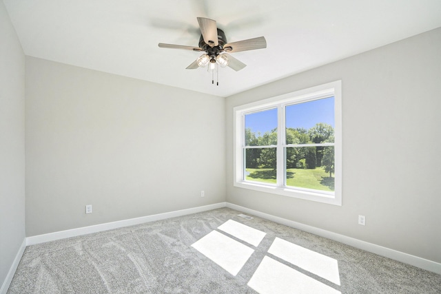 carpeted empty room with visible vents, baseboards, and ceiling fan
