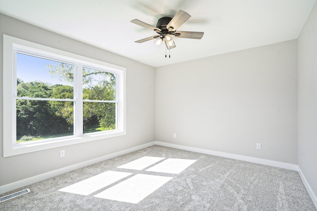carpeted spare room with a ceiling fan, baseboards, and visible vents