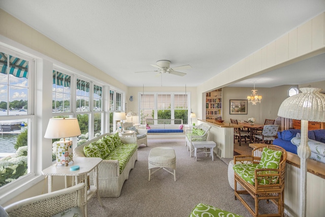 sunroom / solarium with ceiling fan with notable chandelier and a wealth of natural light