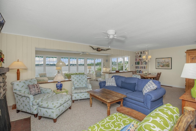 living room featuring carpet floors, ceiling fan with notable chandelier, and a textured ceiling