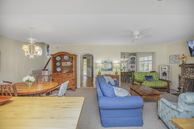 living room with ceiling fan with notable chandelier, light colored carpet, and a fireplace