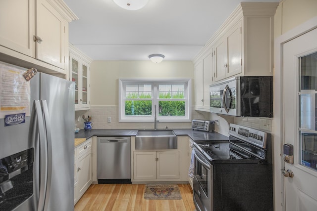 kitchen with sink, stainless steel appliances, light hardwood / wood-style floors, white cabinets, and decorative backsplash