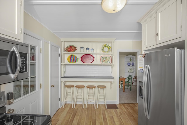 kitchen featuring stainless steel appliances, light wood-type flooring, and white cabinets