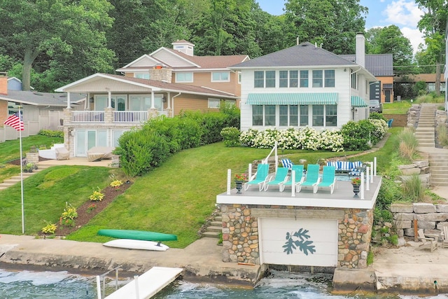 rear view of house featuring a garage, a lawn, and a balcony