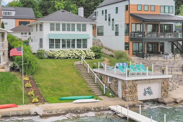 rear view of property featuring a patio area, a lawn, and a water view