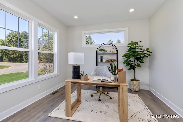 office area with wood finished floors, baseboards, visible vents, and a healthy amount of sunlight