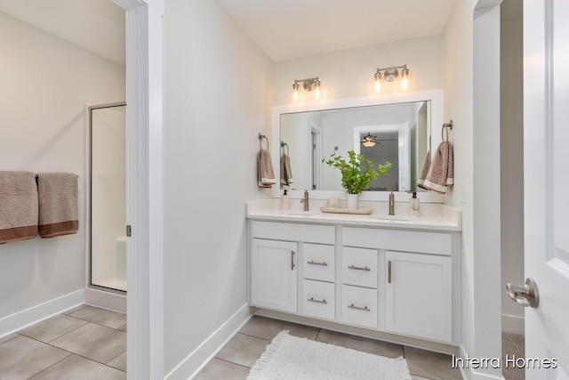 bathroom featuring double vanity, tile patterned floors, a shower stall, and a sink