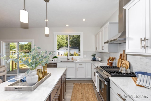 kitchen featuring plenty of natural light, a sink, gas range, wall chimney range hood, and backsplash