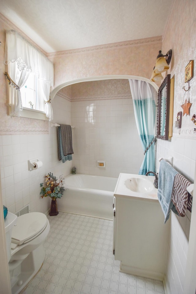 bathroom featuring a textured ceiling, vanity, toilet, and tile walls