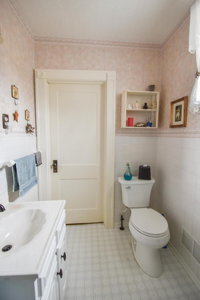 bathroom featuring vanity, toilet, tile walls, and crown molding