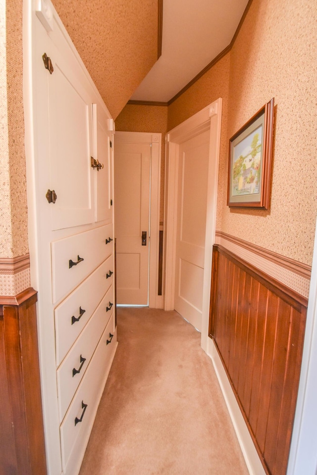 hallway featuring wood walls, crown molding, light carpet, and vaulted ceiling