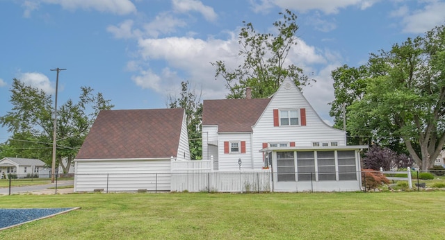 back of house featuring a lawn and a sunroom