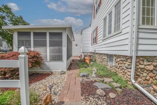 view of home's exterior with a sunroom and central AC