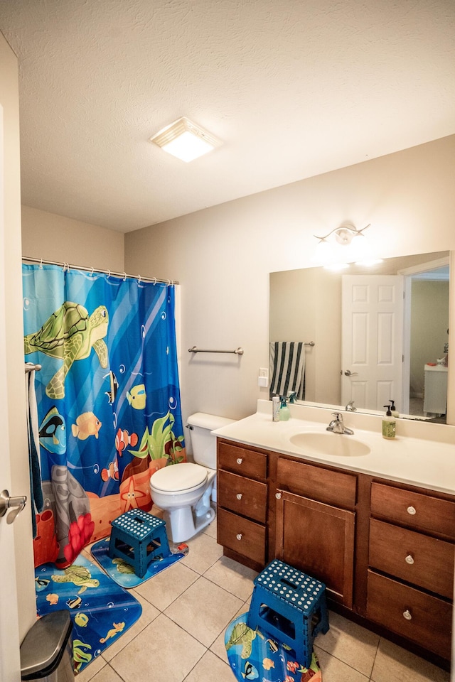 bathroom featuring tile patterned flooring, vanity, a textured ceiling, and toilet