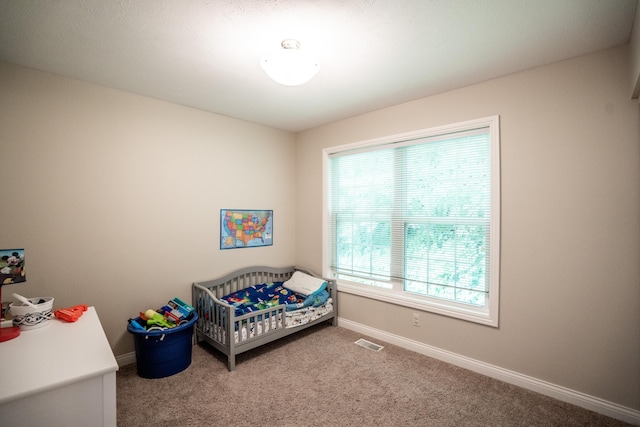 bedroom with a nursery area, multiple windows, and carpet