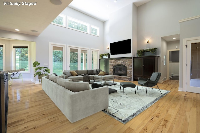 living room featuring a fireplace, a high ceiling, and light hardwood / wood-style flooring