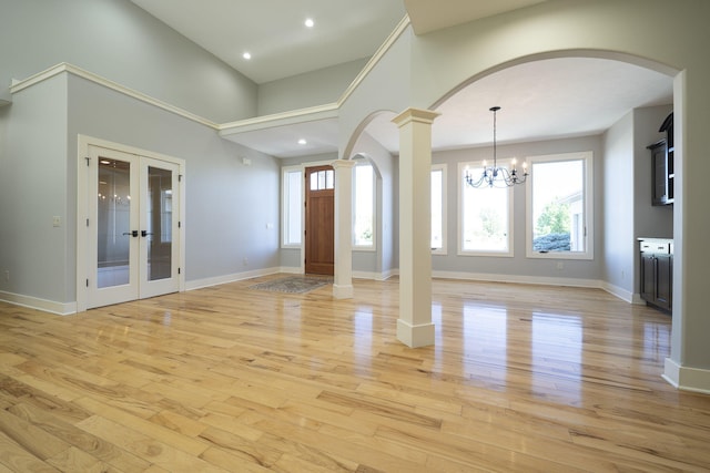 foyer featuring a chandelier, french doors, light wood-type flooring, and decorative columns