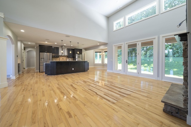 unfurnished living room with light hardwood / wood-style flooring and a high ceiling