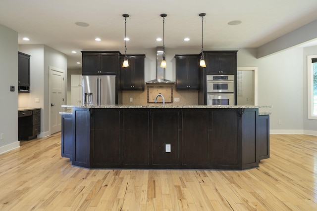 kitchen featuring wall chimney exhaust hood, a spacious island, and stainless steel appliances