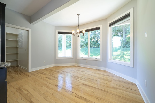 unfurnished dining area with light wood-type flooring and an inviting chandelier