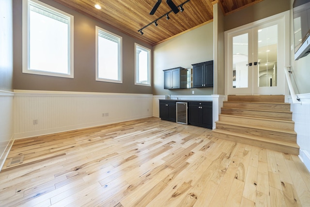 unfurnished living room with light hardwood / wood-style floors, wine cooler, crown molding, and wood ceiling