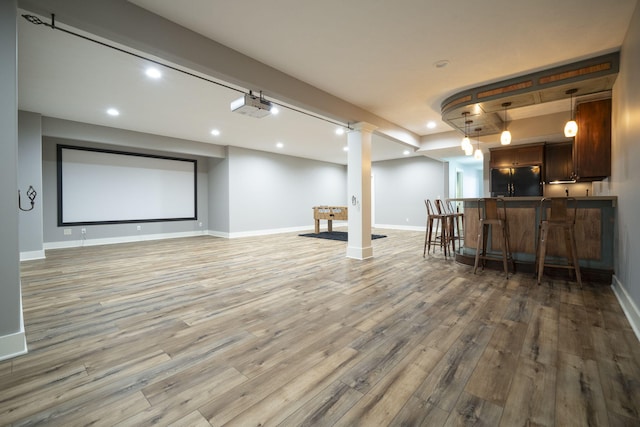 basement featuring black refrigerator, wood-type flooring, and indoor bar