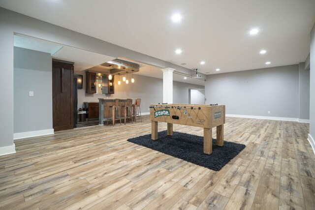 game room with bar area and light hardwood / wood-style flooring