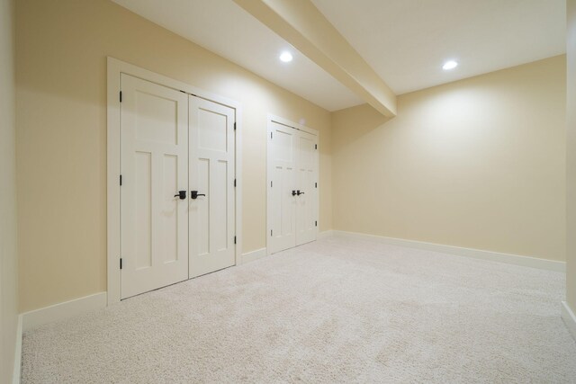 interior space with carpet, beam ceiling, and two closets