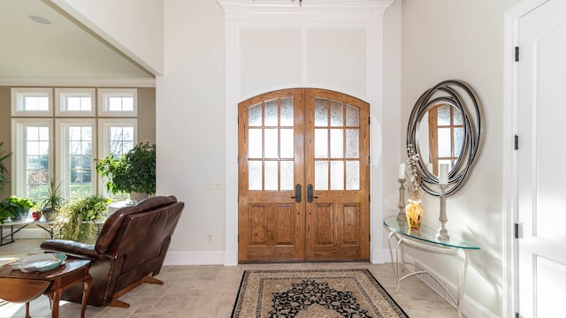 foyer entrance with french doors, plenty of natural light, and crown molding