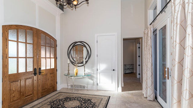 foyer featuring a high ceiling, a chandelier, and french doors