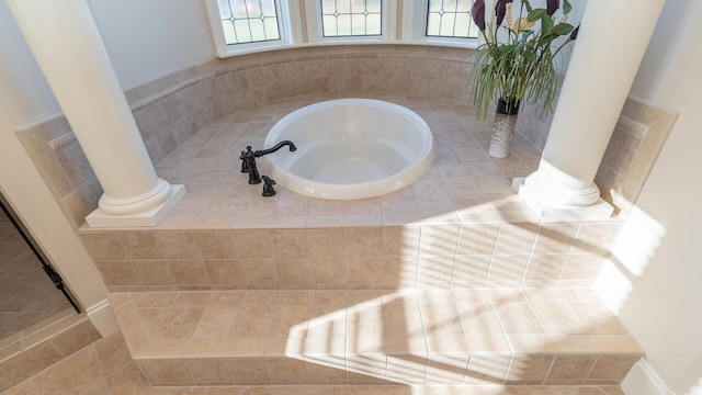 bathroom with ornate columns, tile patterned flooring, and tiled tub