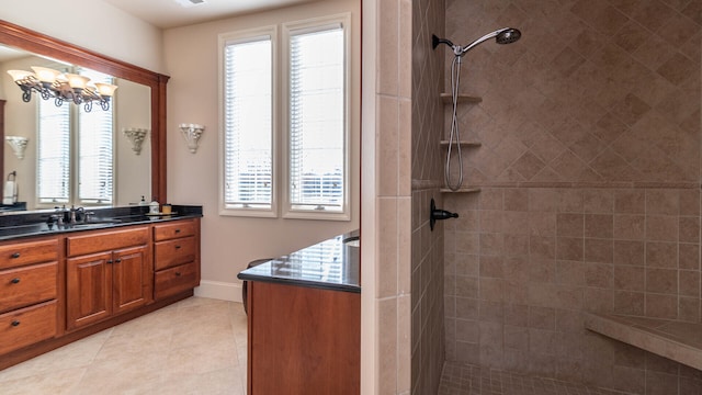 bathroom featuring tile patterned flooring, vanity, tiled shower, and an inviting chandelier