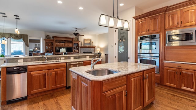 kitchen featuring stainless steel appliances, a center island with sink, and pendant lighting