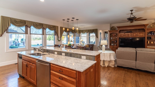 kitchen with pendant lighting, wood-type flooring, sink, and a kitchen island with sink