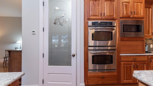 kitchen with light stone counters, decorative backsplash, and appliances with stainless steel finishes