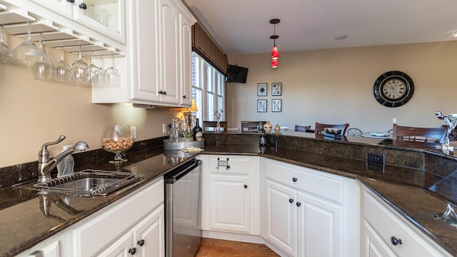 kitchen with pendant lighting, white cabinetry, sink, dark stone counters, and dark wood-type flooring