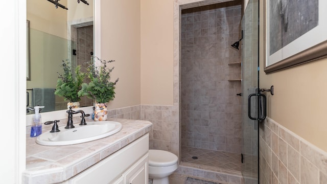 bathroom with vanity, tile walls, walk in shower, and toilet