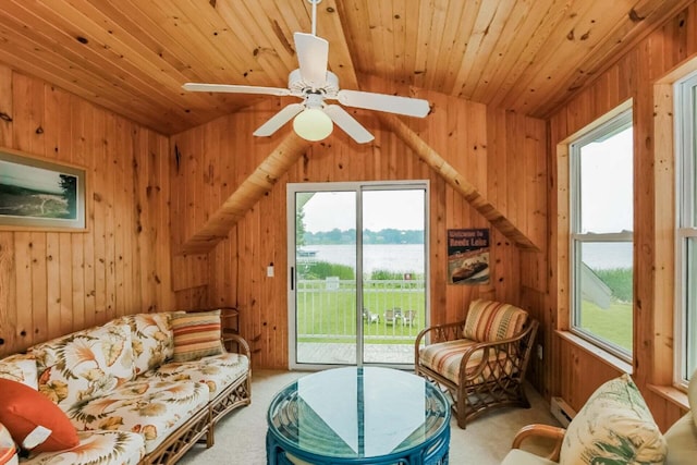 carpeted living room featuring wooden walls, a water view, ceiling fan, and a healthy amount of sunlight