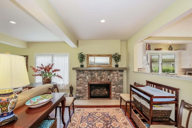 sitting room featuring beam ceiling and a stone fireplace