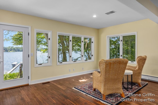 living area featuring wood-type flooring, a water view, and baseboard heating