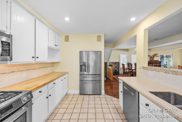 kitchen featuring white cabinets, sink, decorative backsplash, light tile patterned floors, and stainless steel appliances