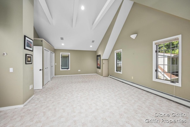 empty room featuring baseboard heating, light carpet, and lofted ceiling