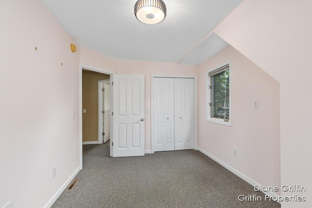 unfurnished bedroom featuring carpet, vaulted ceiling, and a closet