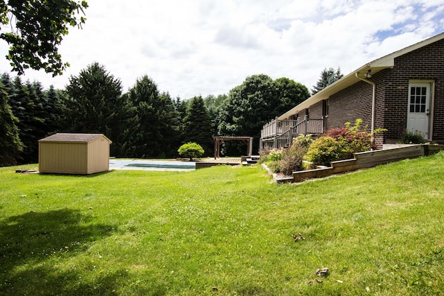 view of yard featuring a pool side deck, a shed, and a pergola