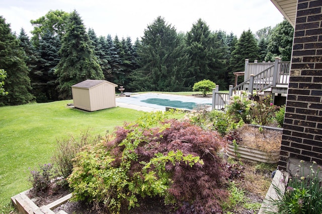 view of yard with a pool side deck and a storage shed